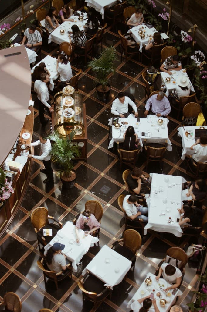 Overhead view of an elegant restaurant with white tablecloths and a black-and-gold marble floor